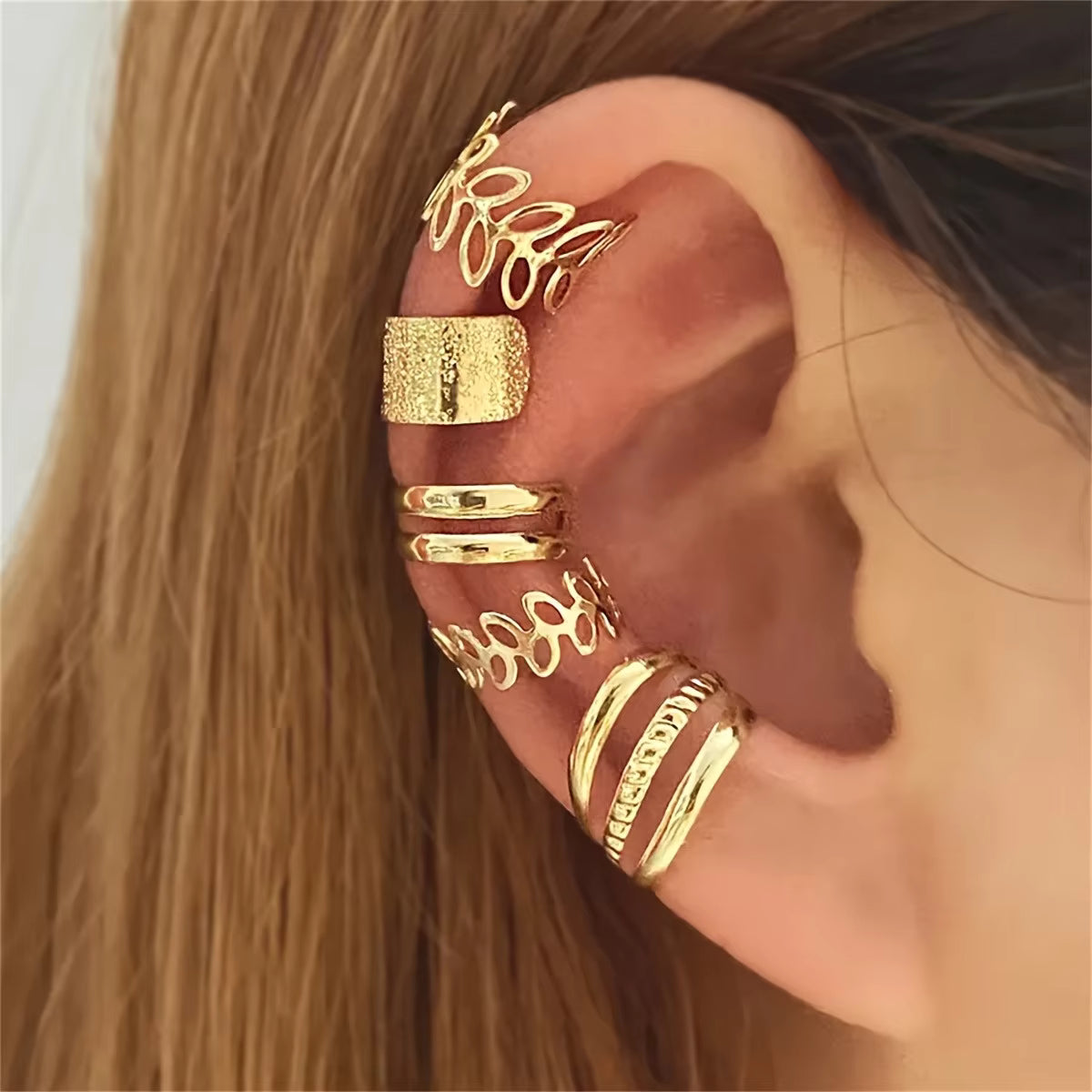 Gold ear cuff worn on an ear with a blurred background