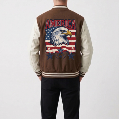 A person shown from the back wearing a brown and cream varsity-style jacket with a large American flag and bald eagle graphic on the back, paired with black pants, against a light gray studio background.