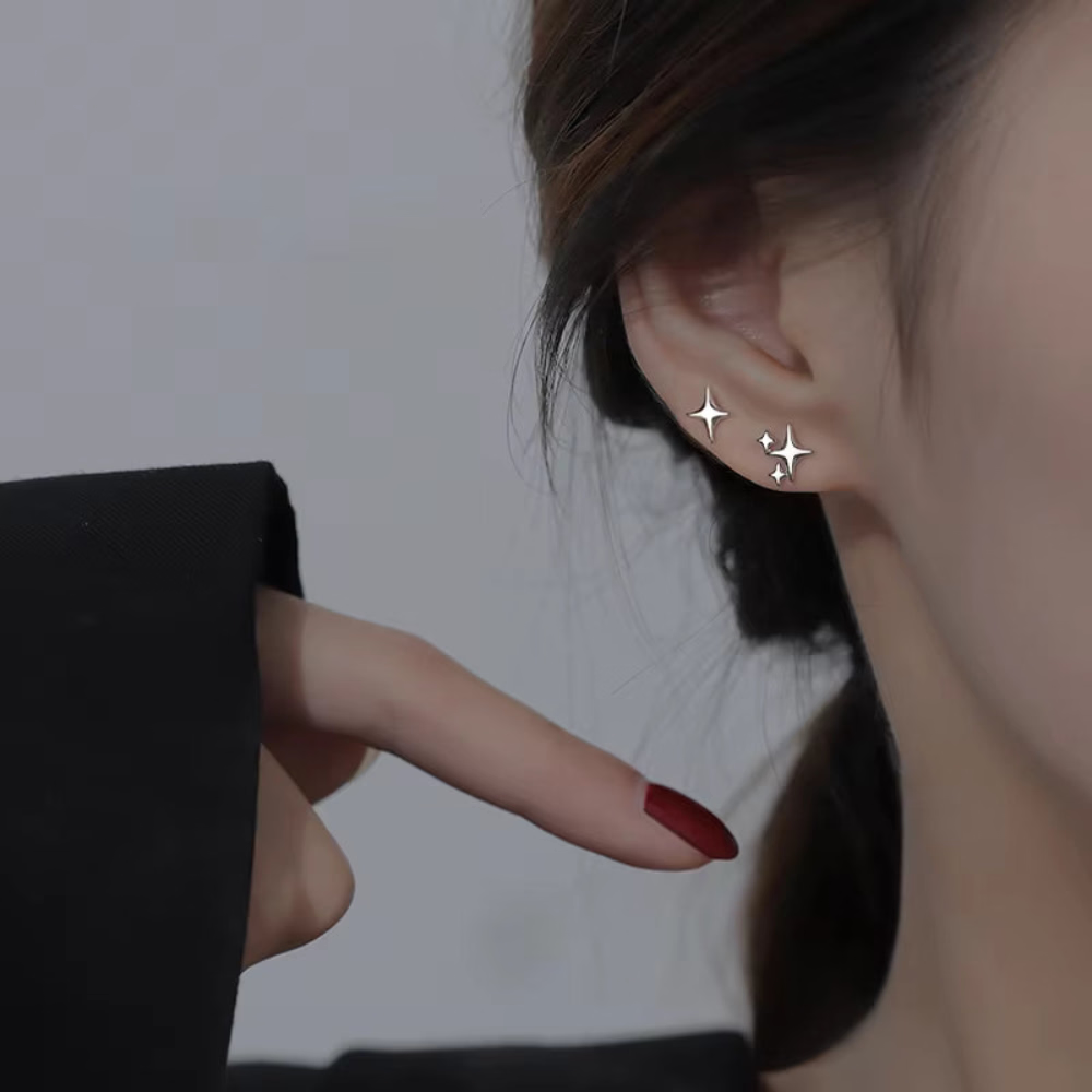 Gold hoop earring being pointed at by a finger with red nail polish.